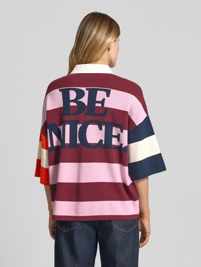 Männermodel trägt Oversized Poloshirt aus Viskose-Mix Modell 'JICE STRIPED EMBO' von Essentiel Antwerp, multikolor, cienki dzianinowy materiał, pasiasty wzór, motyw aplikacji, kołnierz polo, krótka patka na guziki, rękaw 3/4 z prążkowanym mankietem, dół prążkowany. Ganzkörperansicht Rückansicht.