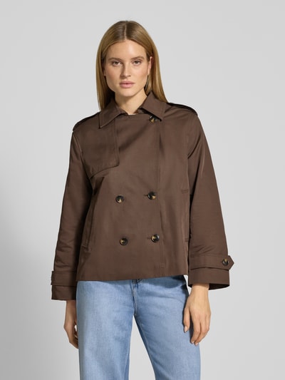 Modelka kobieca ma na sobie Trenchcoat in kurzem Design mit Baumwoll-Anteil von Jake*s Casual, brązowy, prosty krój, dwurzędowe guziki, długość krótka, bawełniany materiał, widoczne kieszenie i pagony, przód, ujęcie całej sylwetki.