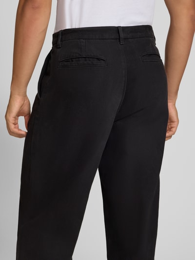 Männermodel trägt Straight Fit Jeans aus reiner bawełna von REVIEW, czarne, wpuszczane kieszenie, zapięcie na guzik i zamek błyskawiczny, szerokość w rozmiarze M 44 cm, długość wewnętrzna nogawki w rozmiarze M 74 cm, widok całej sylwetki z tyłu.