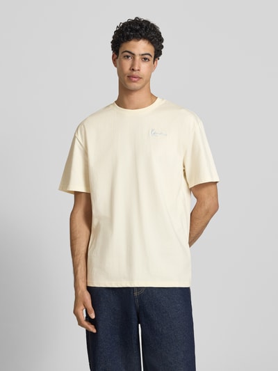 Männermodel trägt Oversized T-Shirt mit rückseitigem Print von KARL KANI aus reiner Baumwolle, Label-Stitching, Rundhalsausschnitt, Vorderansicht, Nahaufnahme Oberkörper.