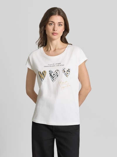 Kobiece model prezentuje Regular Fit T-Shirt mit Viskose-Anteil od Christian Berg Woman, biały, krój regular fit, nadruk z sercami, okrągły dekolt, bawełniany materiał z dodatkiem wiskozy, motyw i napis na przodzie, krótki rękaw, długość pleców w rozmiarze S: 60 cm, widok całej sylwetki z przodu