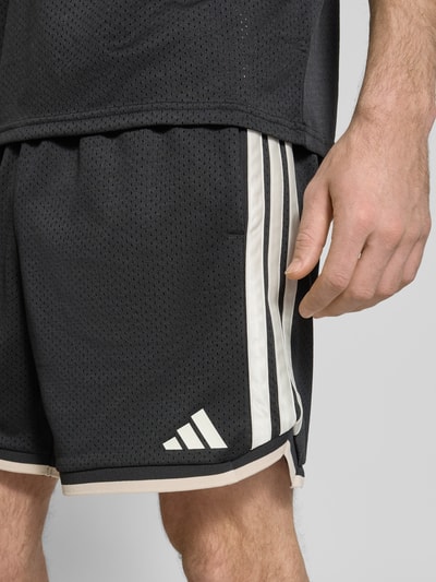 Mężczyzna nosi Shorts mit elastischem Bund und Kordelzug od adidas Sportswear, czarny kolor, luźny krój, logo, Szerokość w rozmiarze M 39 cm, Długość nogawki wewnętrznej 16 cm, zbliżenie na górną część nóg.
