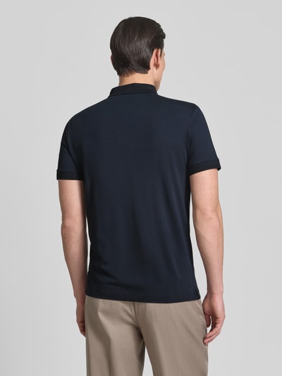 Męski model nosi Regular Fit Poloshirt mit Knopfleiste Modell 'Carlosjuan' von JOOP! Collection, mieszanka bawełny z dodatkiem streczu, krój regular fit, kołnierzyk polo, krótka listwa guzikowa, długość tyłu w rozmiarze M: 69 cm, gładka faktura, kolor granatowy i beżowy, Ganzkörperansicht Rückansicht.