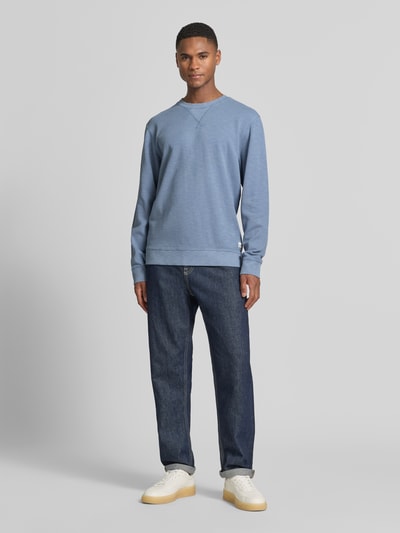 Männermodel trägt Regular Fit Sweatshirt mit Rundhalsausschnitt von Scotch & Soda in Blau, Baumwoll-Mix, Label-Detail, Ganzkörperansicht von vorne.
