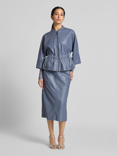 Frauenmodel trägt Blazer in Leder-Optik mit Stehkragen von Marc Cain in Blau, taillierte Passform, Reißverschluss, 3/4-Arm, Ganzkörperansicht von vorne.