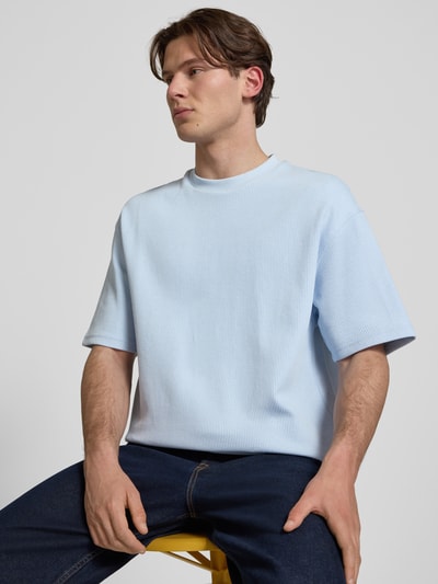 Männermodel trägt Relaxed Fit T-Shirt aus Baumwoll-Mix Modell 'NUWAFFLE' von HUGO, Optik: Unifarben, Struktur, Label-Stitching-Applikation, Rundhals, Kurzarm, Farbe Hellblau, Muster Struktur, Ganzkörperansicht von vorne.