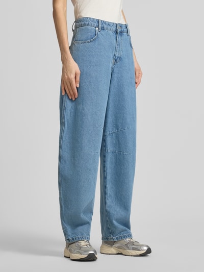 Frauenmodel trägt Barrel Fit Jeans mit Eingrifftaschen Modell 'Alannah' von Neo Noir aus reiner Baumwolle in mittlerem Blau, Ganzkörperansicht von vorne.