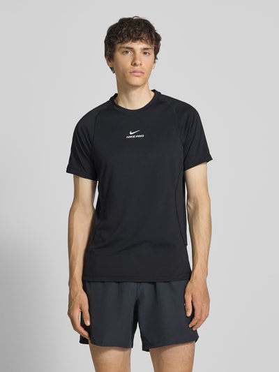 Männermodel trägt T-Shirt mit Logo-Print und Raglanärmeln von NIKE TRAINING in Schwarz, Straight Fit, Rundhalsausschnitt, Ganzkörperansicht von vorne, Rückenlänge bei Größe M 71 cm.