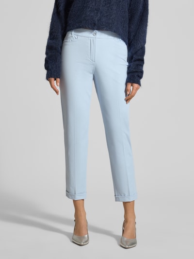 Frauenmodel trägt hellblaue Damen Chino aus Techno Cotton Superstretch Modell 'UTE' von Raffaello Rossi, Straight Fit, verkürzt, Knopf- und Reißverschluss, Elastischer-Material-Mix mit Baumwoll-Anteil, Eingriff- und Gesäßtaschen, Bügelfalten, fixierte Beinumschläge, Gürtelschlaufen, glatte Textur, Ganzkörperansicht von vorne.