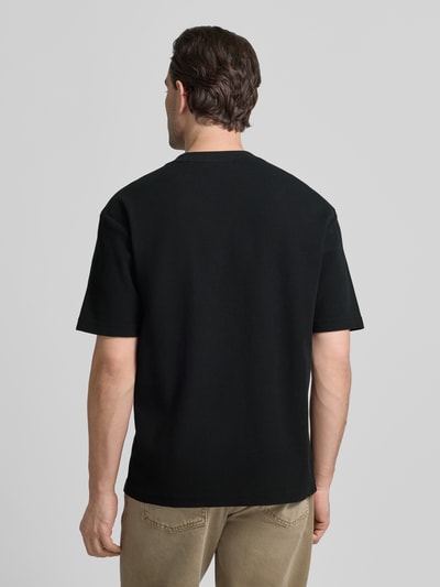 Männermodel trägt Regular Fit T-Shirt aus reiner Baumwolle Modell 'DAFFL' von HUGO in Schwarz, strukturierte Optik, Ganzkörperansicht Rückansicht.