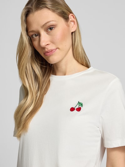 Frauenmodel trägt Damen T-Shirt aus Reine Baumwolle mit Kirschstickerei, Modell 'SYBILLA' von Vila, Gerader-Schnitt, Rundhalsausschnitt, Nahaufnahme Oberkörper. Rückenlänge bei Größe S: 58 cm.