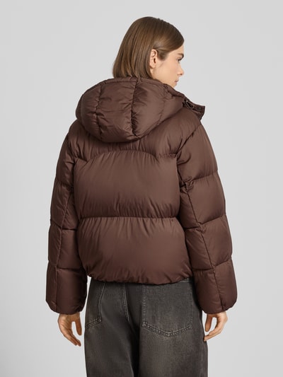 Modelka kobieca nosi Regular Fit Steppjacke mit Kapuze Modell 'Bubble' od Levi's®, brązowa, pikowana tekstura, widok całej sylwetki od tyłu, kurtka z kapturem, kieszenie na zatrzaski, elastyczne wykończenia, długość 57 cm, szerokość ramion 47 cm, szerokość klatki piersiowej 58 cm, długość rękawa 58 cm.