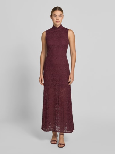 Frauenmodel trägt Maxikleid mit Allover-Spitzenbesatz von ROTATE, elastischer Material-Mix mit Baumwoll-Anteil, Slim-Fit, Stehkragen, ärmelloses Design, bordeauxrote Farbe, dezente Spitzenstruktur, Gesamtlänge 144 cm, Brustweite 44 cm, Ganzkörperansicht von vorne.