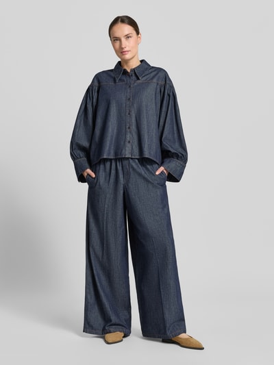 Kobiece modelka ma na sobie Relaxed Fit Jeansbluse Modell 'SELENI' od Drykorn, ciemnoniebieska bawełna, guziki, kołnierzyk koszulowy, długość tyłu 64 cm, długość rękawa 57 cm, widok całej sylwetki z przodu.