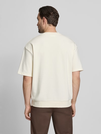 Männermodel trägt Oversized T-Shirt mit Rundhalsausschnitt von Lindbergh aus Baumwoll-Mix, cremefarben, Label-Detail, Rückenlänge 70 cm, Ganzkörperansicht Rückansicht.