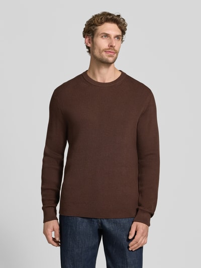 Męski model nosi Regular Fit Strickpullover aus Baumwoll-Mix od MCNEAL, mieszanka bawełny, okrągły dekolt, elastyczne wykończenia, długość tyłu w rozmiarze M: 65 cm, długość rękawów w rozmiarze M: 56 cm, brązowy, prosta faktura, widok całej sylwetki z przodu.
