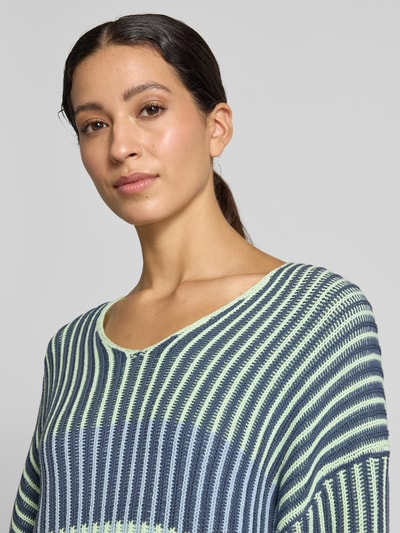 Frauenmodel trägt Oversized Strickpullover mit V-Ausschnitt von Marc Cain, Baumwoll-Mix, gerippte Struktur, Nahaufnahme Oberkörper.
