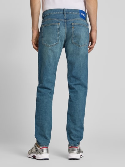 Männermodel trägt Straight Fit Jeans aus Baumwoll-Mix Modell 'Brody' von HUGO in Denim-Optik mit Label-Patch, Nieten, 5-Pocket-Design, Ganzkörperansicht Rückansicht.