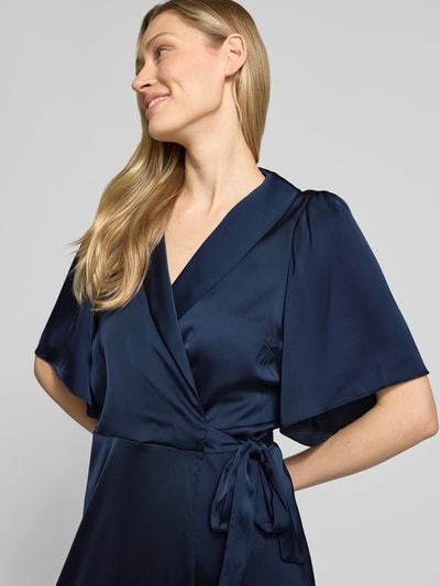 Frauenmodel trägt Midikleid in Wickel-Optik Modell 'VIENNA RAVENNA' von Vila aus dunkelblauem Satin, Nahaufnahme Oberkörper, taillierter Schnitt, V-Ausschnitt, seidige Textur, Kontext: Rückenlänge bei Größe 36: 125 cm, Brustweite: 50 cm, Ärmellänge: 30 cm.