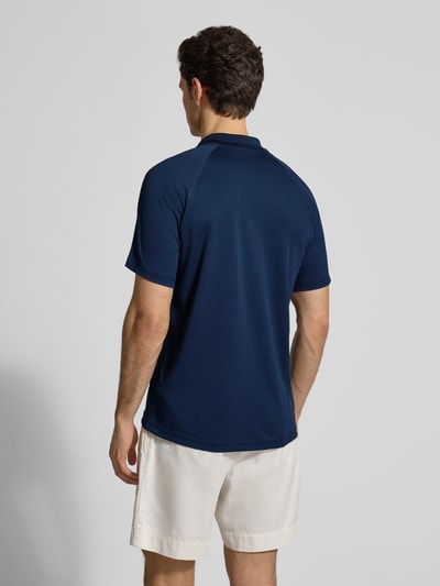Męski model nosi Regular Fit Sport Poloshirt mit Label Patch od Lacoste, efekt: jednolity kolor, krój regular fit, naszywka z logo, kołnierzyk polo, zapięcie na 3 guziki, krótki rękaw, wykończenie materiału: pika, całkowity widok z tyłu.