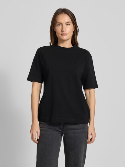 Frauenmodel trägt T-Shirt mit Label-Stitching Modell 'TARJAA' von ARMEDANGELS aus Bio-Baumwolle, schwarz, lockerer Schnitt, Ganzkörperansicht von vorne.