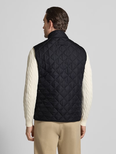 Męski model nosi Regular Fit Steppweste mit Stehkragen od Barbour, czarna, jednolity wzór, krój regular fit, widok całej sylwetki od tyłu.