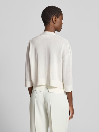 Männermodel trägt Strickjacke aus Lyocell-Baumwoll-Mix in offener Passform von comma, kolor kremowy, gładka tekstura, krój regular fit, rękaw o dł. 3/4, długość tyłu w rozmiarze S 43 cm, długość rękawa w rozmiarze S 32 cm, Ganzkörperansicht Rückansicht.