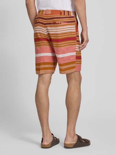 Männermodel trägt Shorts mit Eingrifftaschen von Zuitable aus katoenmix, regular fit, all-over look, bandwijdte maat M 40 cm, binnenbeenlengte 24 cm, geheel in warme rood- en oranje tinten met horizontale strepen, steekzakken, ganzkörperaanzicht rugaanzicht.