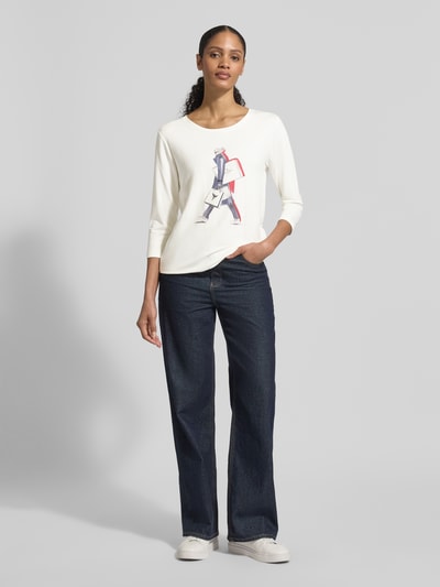Frauenmodel trägt Regular Fit Longsleeve aus Viskose-Mix mit Ziersteinbesatz von monari, elastischer Viskose-Mix, Logo-Print, 7/8-Arm, weißer Rundhalsausschnitt, Motiv-Print, Rückenlänge 59 cm bei Größe 36, Ganzkörperansicht von vorne.