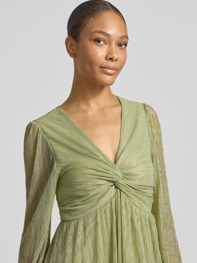 Frauenmodel trägt Tailliertes Freizeitkleid mit Unterkleid von s.Oliver BLACK LABEL in grün, Metalic-Optik, Crinkle-Optik, V-Ausschnitt, Langarm, Nahaufnahme Oberkörper.