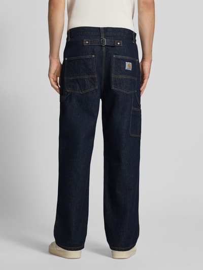 Männermodel trägt Relaxed Fit Jeans Modell 'Belmont' von Carhartt Work In Progress aus Reine Baumwolle, dunkles Blau, sichtbare Nähte, mit Eingrifftaschen, Bundweite 43 cm, Innenbeinlänge 76 cm, Ganzkörperansicht Rückansicht.