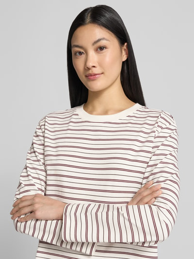 Frauenmodel trägt Boxy Fit Langarmshirt aus reiner Baumwolle Modell 'ESSENTIAL' von Selected, cremefarben mit roten Streifen, Damen Langarmshirt, Nahaufnahme Oberkörper.