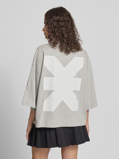 Modelka nosi Oversized T-Shirt mit Rundhalsausschnitt von Karo Kauer z bawełny, krój oversized, krój krótki, nadruk z logo, długość tyłu w rozmiarze S: 61 cm, widok całej sylwetki z tyłu.