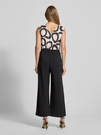 Frauenmodel trägt Jumpsuit mit Eingrifftaschen Modell 'Bi44lina' von ZABAIONE, Material-Mix mit Stretch-Anteil, weites Bein, V-Ausschnitt, Schwarz, Ganzkörperansicht Rückansicht.