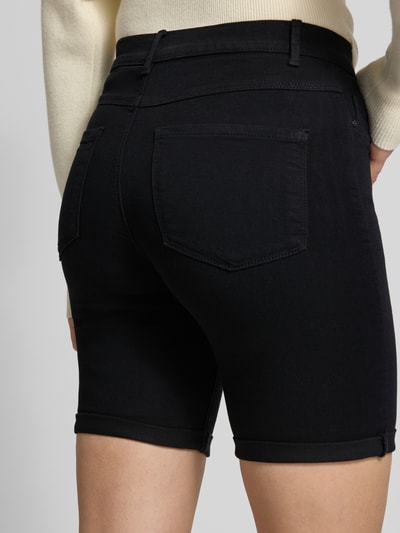 Frauenmodel trägt Slim Fit Jeansshorts mit fixiertem Umschlag Modell 'RAIN' von Only in dunkler Denim-Optik, Viskose-Mix, 5-Pocket-Design, Ganzkörperansicht Rückansicht.