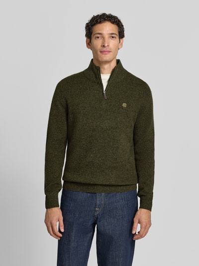 Männermodel trägt Regular Fit Strickpullover aus reiner Wolle von MCNEAL in Olivgrün mit Troyer-Kragen und Rippbündchen, Ganzkörperansicht von vorne.
