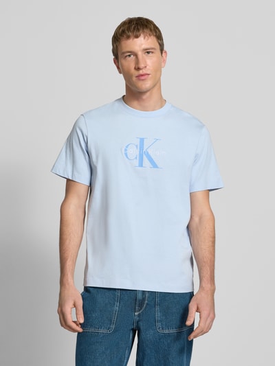 Männermodel trägt T-Shirt mit Label-Print und Rundhalsausschnitt von Calvin Klein Jeans in Hellblau, Regular-Fit, Reine Baumwolle, Ganzkörperansicht von vorne.