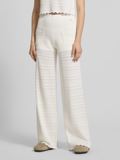 Frauenmodel trägt Strickhose mit Eingrifftaschen Modell 'Aurea' von OH APRIL aus Baumwoll-Viskose-Mix, Flared Fit, Label-Patch, Ganzkörperansicht von vorne.