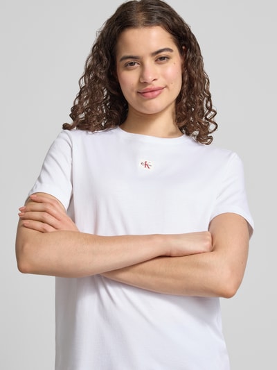 Frauenmodel trägt Regular Fit T-Shirt aus reiner Baumwolle von Calvin Klein Jeans in Weiß mit kleinem Logo, Nahaufnahme Oberkörper.