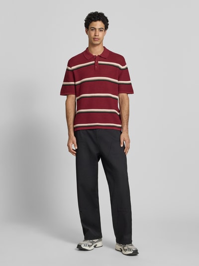 Männermodel trägt Regular Fit Poloshirt mit Streifenmuster Modell 'MAINE' von Jack & Jones aus reiner Baumwolle, Ganzkörperansicht von vorne.