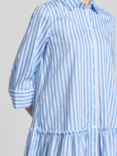 Frauenmodel trägt Relaxed Fit Hemdblusenkleid mit Rüschenbesatz von Christian Berg Woman, Reine Baumwolle, 3/4-Arm, vertikale blaue und weiße Streifen, Knopfleiste, Hemdblusenkragen, Nahaufnahme Oberkörper.