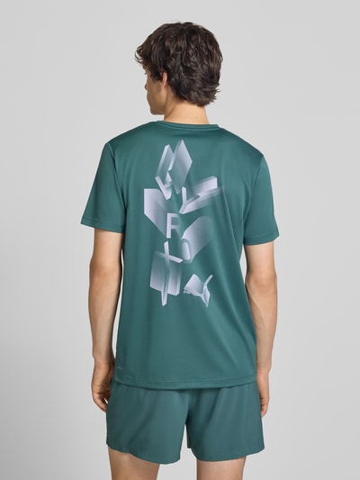 Männermodel trägt Regular Fit Sport-T-Shirt mit Logo-Print Modell 'M PUMA X HYROX' von PUMA in Grün, glatte Textur, Herren Sport-T-Shirt, Ganzkörperansicht Rückansicht.