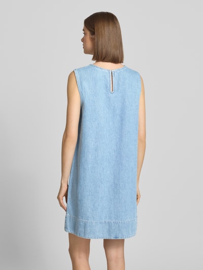 Frauenmodel trägt Relaxed Fit Jeanskleid aus reiner Baumwolle Modell 'FLORA' von Pieces in Denim-Optik und Mini-Länge, Ganzkörperansicht Rückansicht.