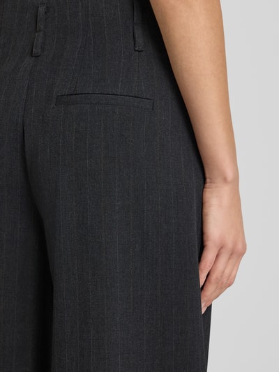 Kobiece modelka nosi spodnie materiałowe High Waist z szerokimi nogawkami Model 'Luna' od My Essential Wardrobe, mieszanka materiałów z dodatkiem wiskozy, kolor ciemnoszary, delikatne pionowe paski, widoczna tylna kieszeń, kontekst: szerokość w pasie 39 cm, długość wewnętrzna nogawki 80 cm, detailaufnahme okolicy biodra.