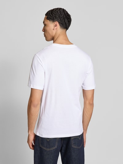 Männermodel trägt Regular Fit T-Shirt aus reiner Baumwolle Modell 'COLE' von Jack & Jones in Weiß mit Label-Print, Ganzkörperansicht Rückansicht. Herren T-Shirt, Rundhalsausschnitt, Rückenlänge bei Größe M 70 cm, glatte Textur, schlichte Optik.