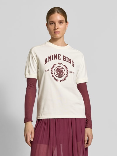 Frauenmodel trägt Regular Fit T-Shirt aus reiner Baumwolle von Anine Bing, Logo-Print und Rundhalsausschnitt, creme-weiß und bordeaux, Ganzkörperansicht von vorne. Rückenlänge bei Größe S: 56 cm, Damen T-Shirt, Logo-Stitching.