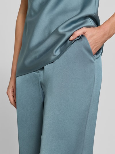 Frauenmodel trägt Wide Fit Hose mit Bundfalten von SWING in hellblau, taschenloses Design, glatte Textur, Nahaufnahme Oberkörper.