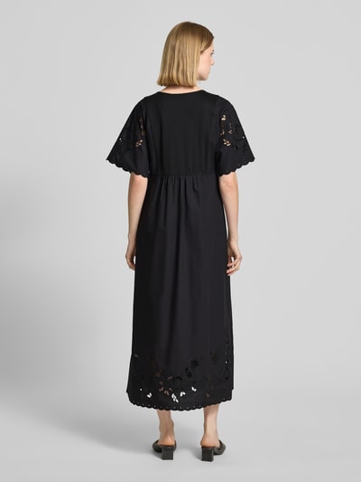 Vrouwenmodel draagt vrijetijdsjurk Fließendes Freizeitkleid aus reiner Baumwolle Modell 'TARTUFO' van Weekend Max Mara in effen zwart met broderie, maxi lengte, V-hals, korte mouw, rechte zoom, jersey en popeline van puur katoen, geheelopname achteraan.