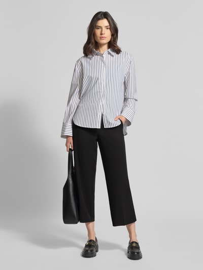 Frauenmodel trägt Hose mit verkürzter Passform Modell 'Hillda-650' von STEHMANN, schwarzer Material-Mix mit Stretch-Anteil, Bügelfalten, Ganzkörperansicht von vorne.