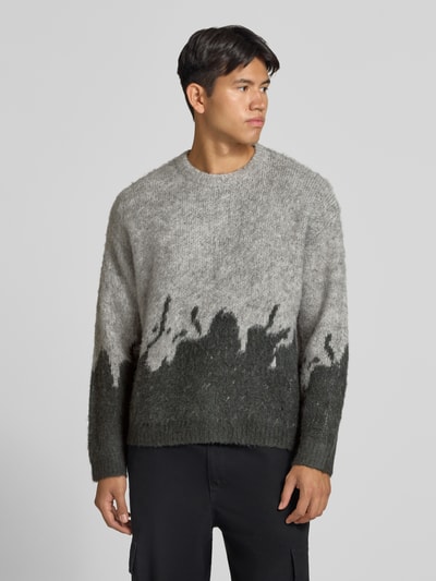 Männermodel trägt Strickpullover mit gerippten Abschlüssen von ANOTHER COTTON LAB in Grau, lockerer Schnitt, melierte Textur, Nahaufnahme Oberkörper. Elastischer Material-Mix mit Lanawoll-Anteil, Rundhalsausschnitt, überschnittene Ärmel, Rückenlänge 62 cm, Ärmellänge 67 cm.